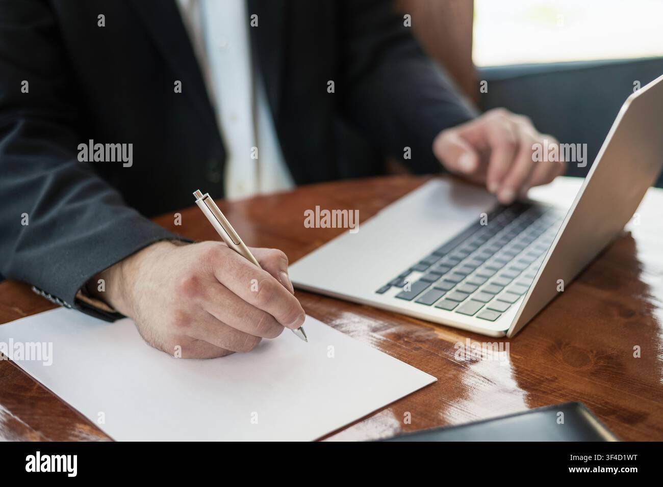 Businessman writing notes while working on laptop Stock Photo