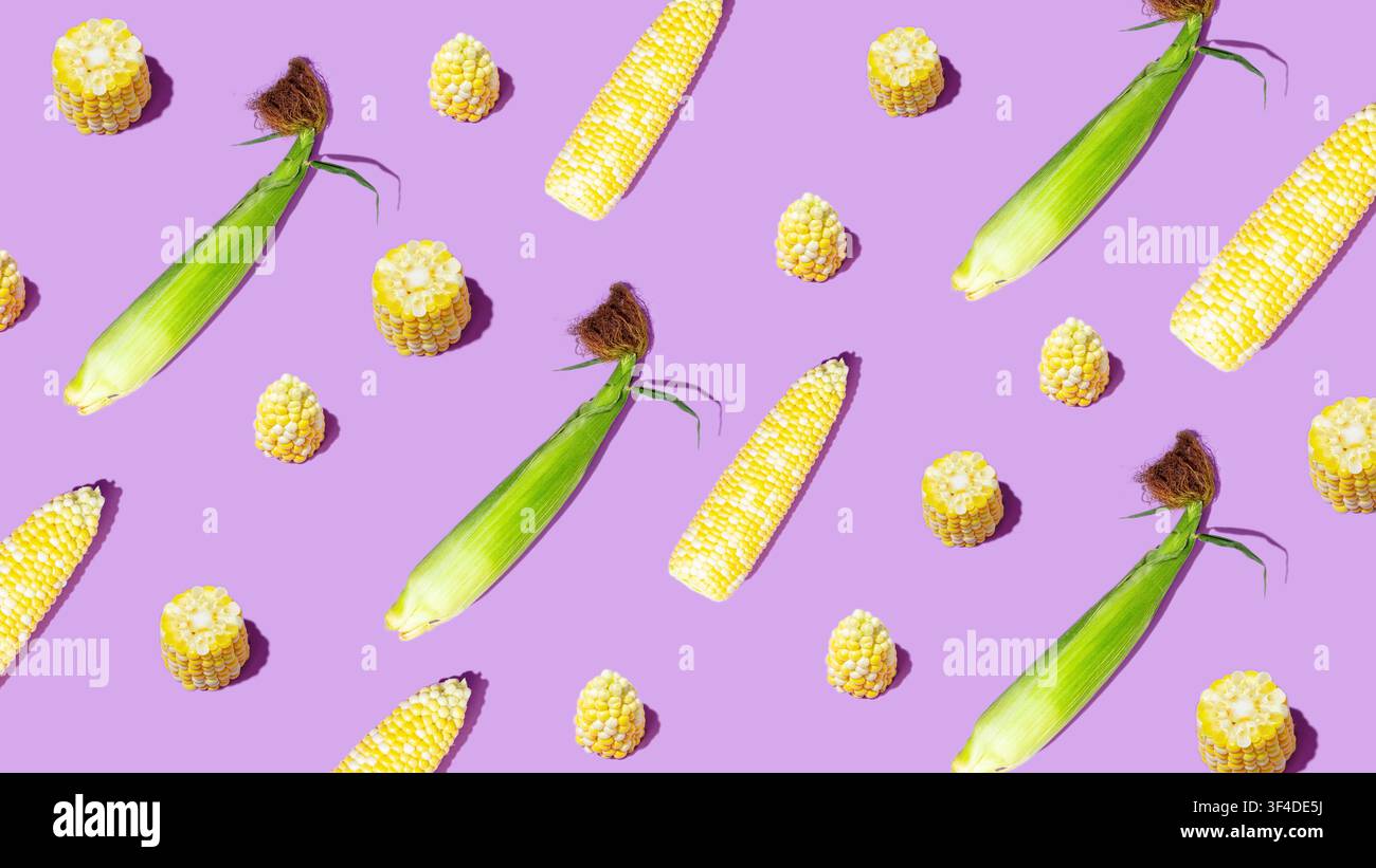 Corn cobs and kernels arranged in playful pattern on purple background Stock Photo
