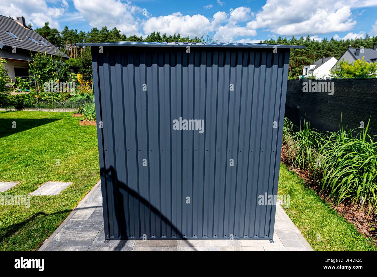 Anthracite garden shed providing functional storage solution along property line Stock Photo