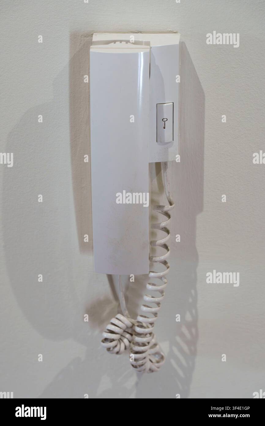 White intercom phone mounted on a wall inside a building interior Stock Photo
