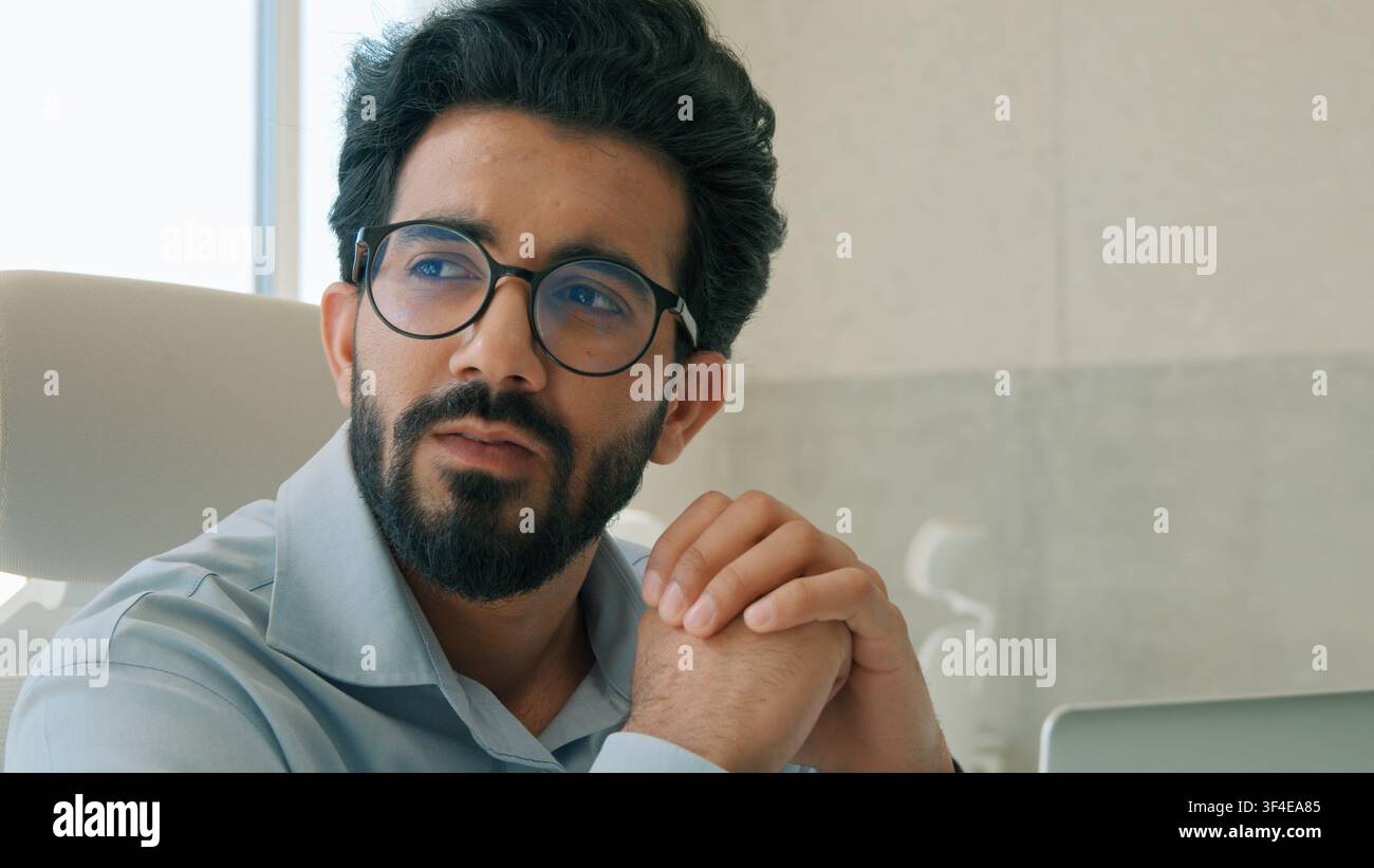 Thoughtful pensive Arabian businessman Indian man entrepreneur working computer in office analyzing online business project thinking solving problem Stock Photo