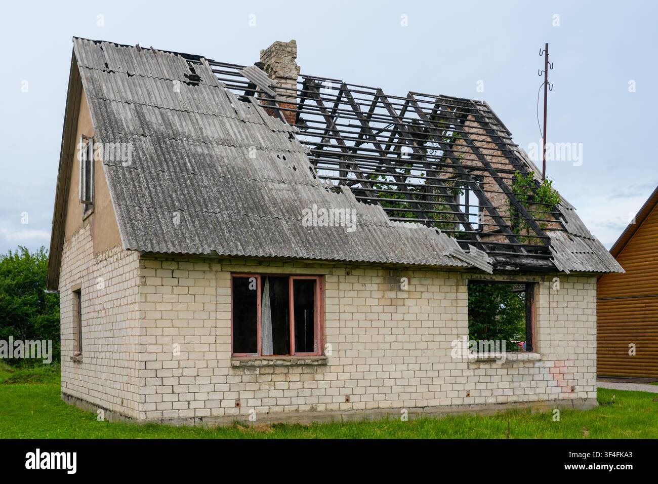 Fire Damaged Abandoned Brick House with Collapsed Roof Structure and Severe Structural Damage Exterior Stock Photo