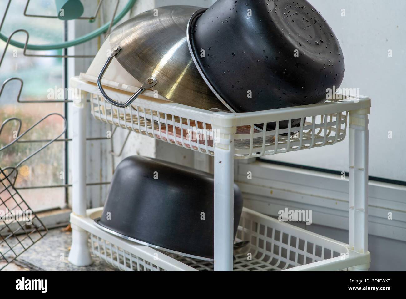 Stacked kitchen bowls drying in wire rack Stock Photo