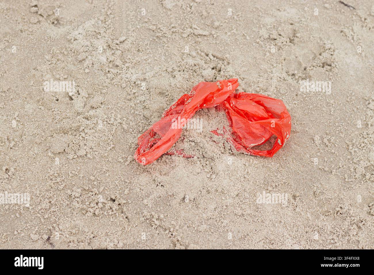 Red plastic bag on sandy beach Stock Photo