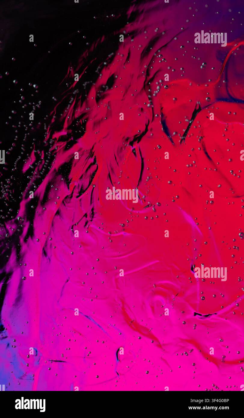 Abstract magenta and red liquid creating a dynamic swirling pattern with small bubbles Stock Photo
