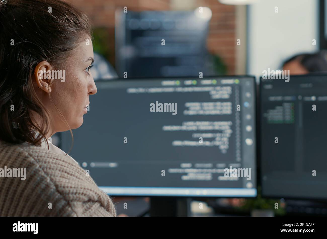 Database Designer Coding Across Multiple Screens in a software development office, showing programmers collaborating on source code, algorithms and data coding workflow. Stock Photo