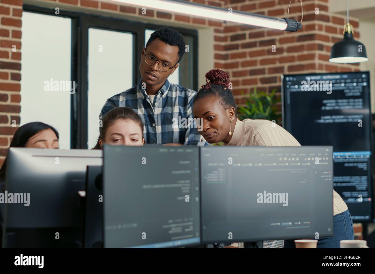 Developers Brainstorming Code Feedback with Intern in a software development office, showing programmers collaborating on source code, algorithms and data coding workflow. Stock Photo