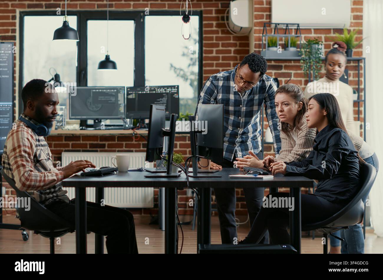 Junior developers asking senior programmer for algorithm help in a software office, showing source code, programming workflow and technical collaboration on digital development tasks. Stock Photo