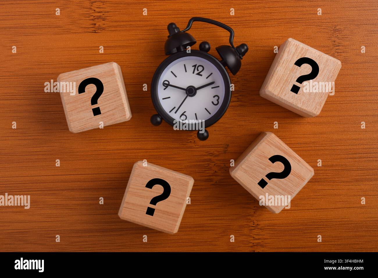 Question mark blocks with alarm clock on wooden background representing ...