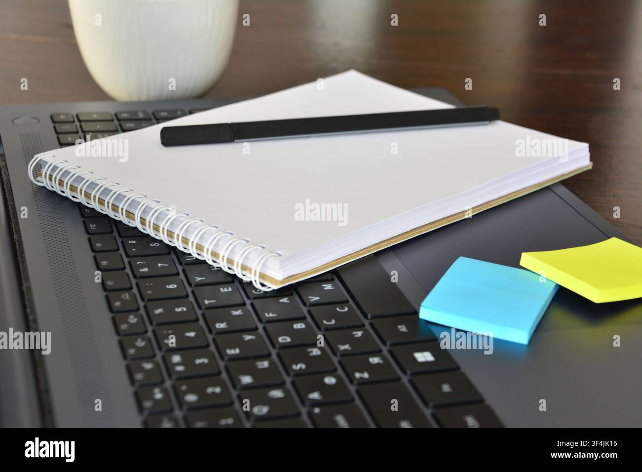 Notebook and Pen on Laptop Keyboard with Sticky Notes front view Stock Photo
