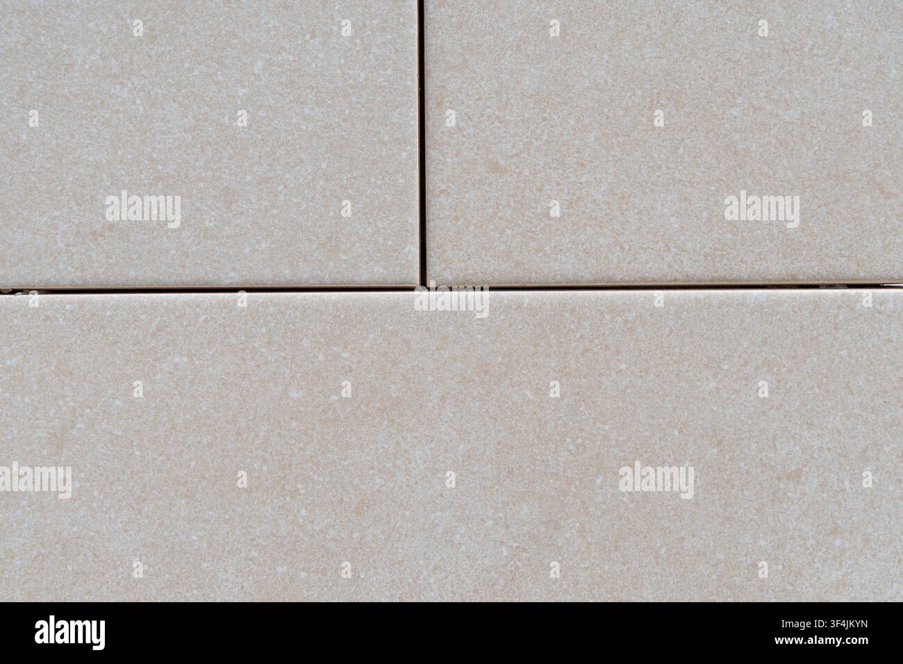 A detailed view of neutral-colored rectangular tiles, showcasing their speckled surface and the thin dark lines between them Stock Photo