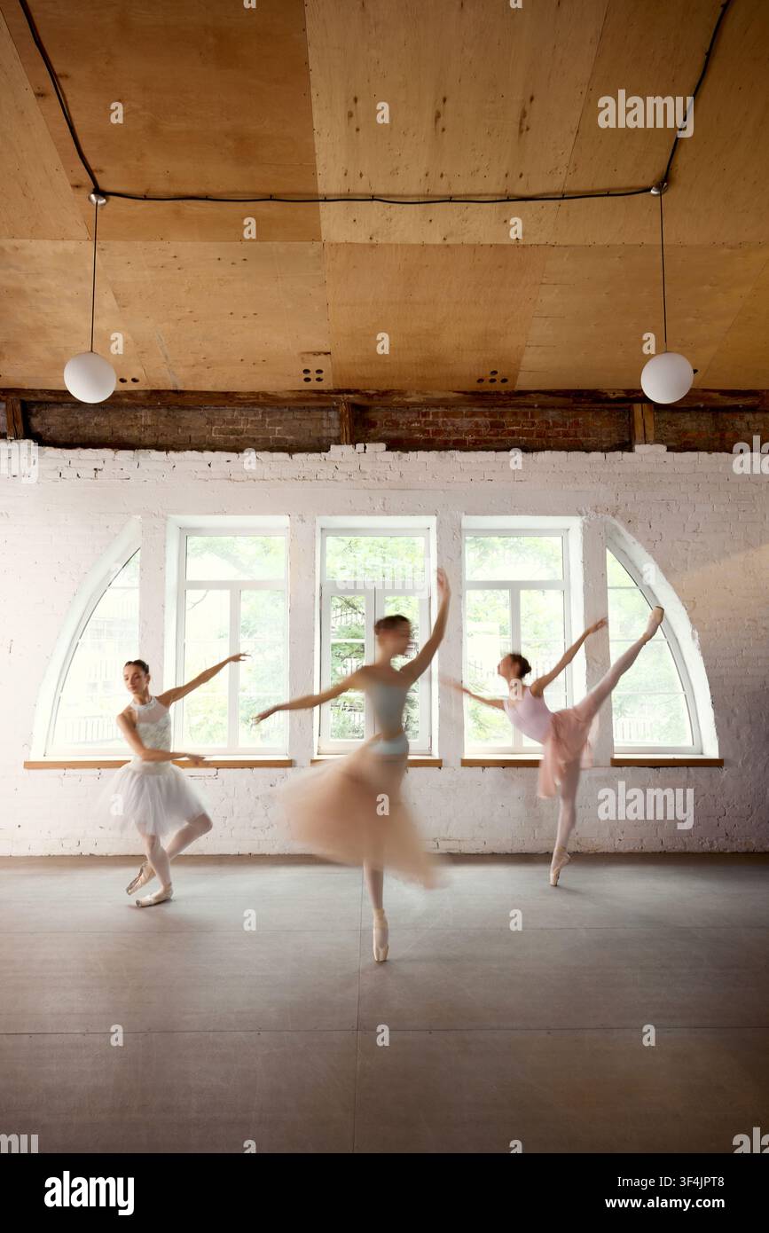 Ballet dancers rehearsing energetic group sequence in sunlit studio Stock Photo