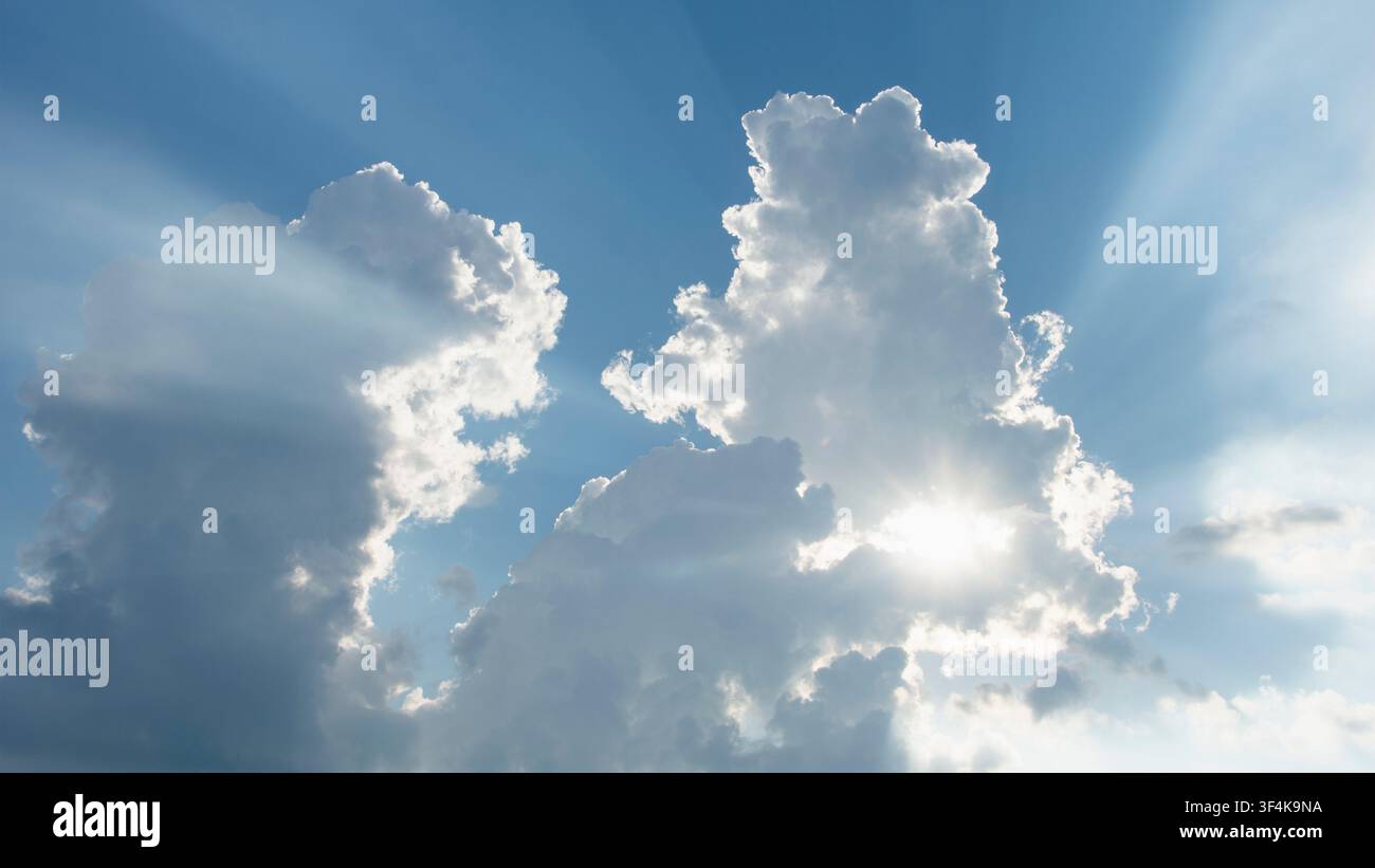 Sun shining through white puffy clouds Stock Photo