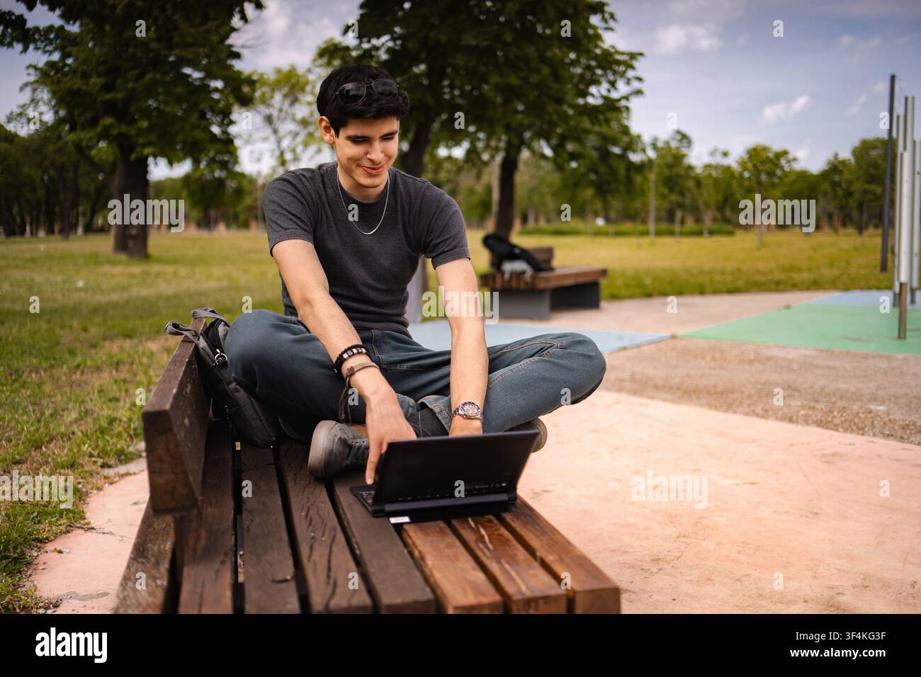 Young man using laptop smiling working remotely in park Stock Photo