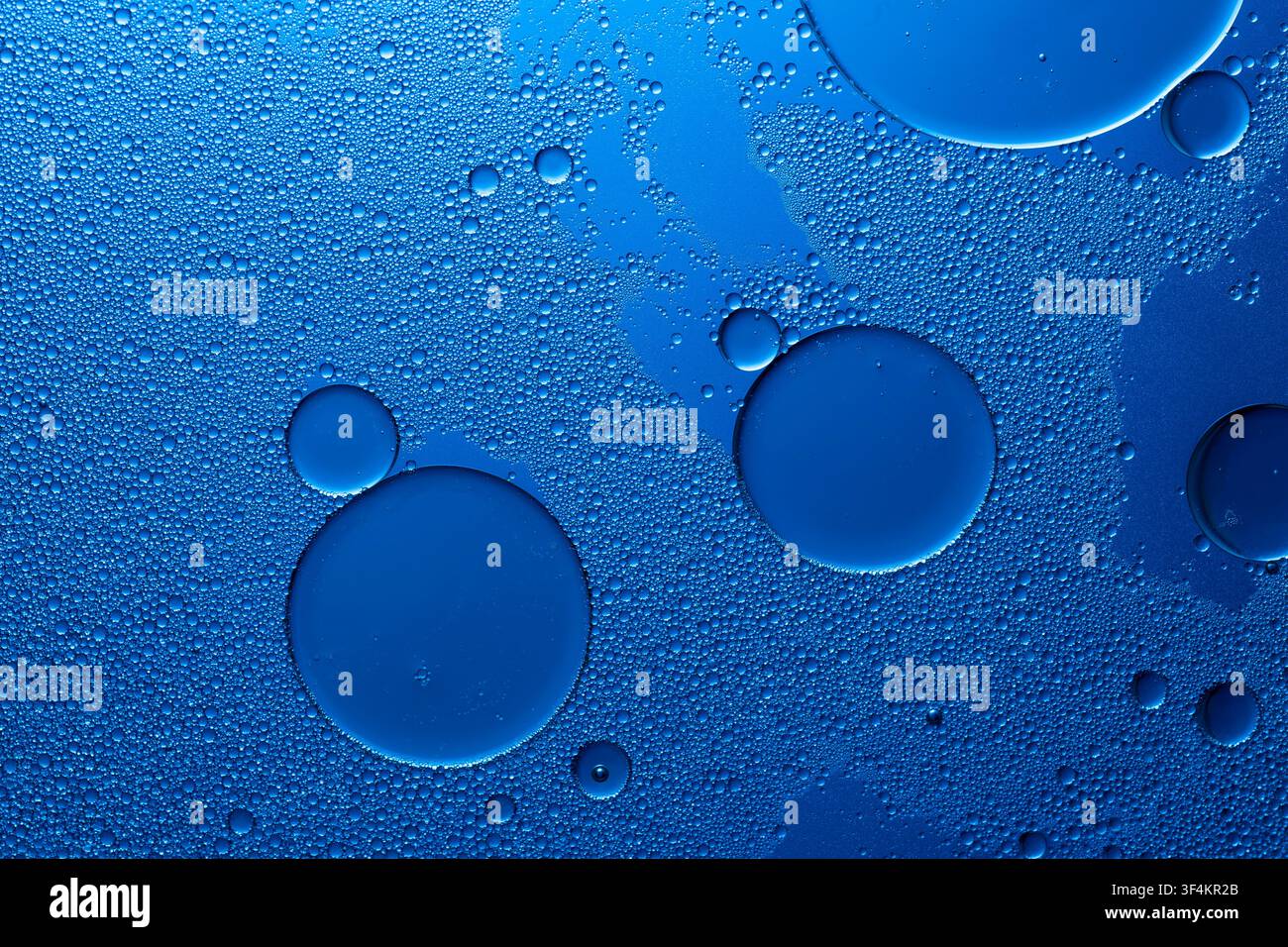 Oil drops on water surface creating blue abstract background with bubbles and texture Stock Photo