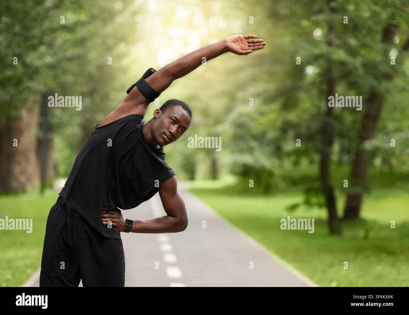 Athletic black guy stretching before training at park Stock Photo