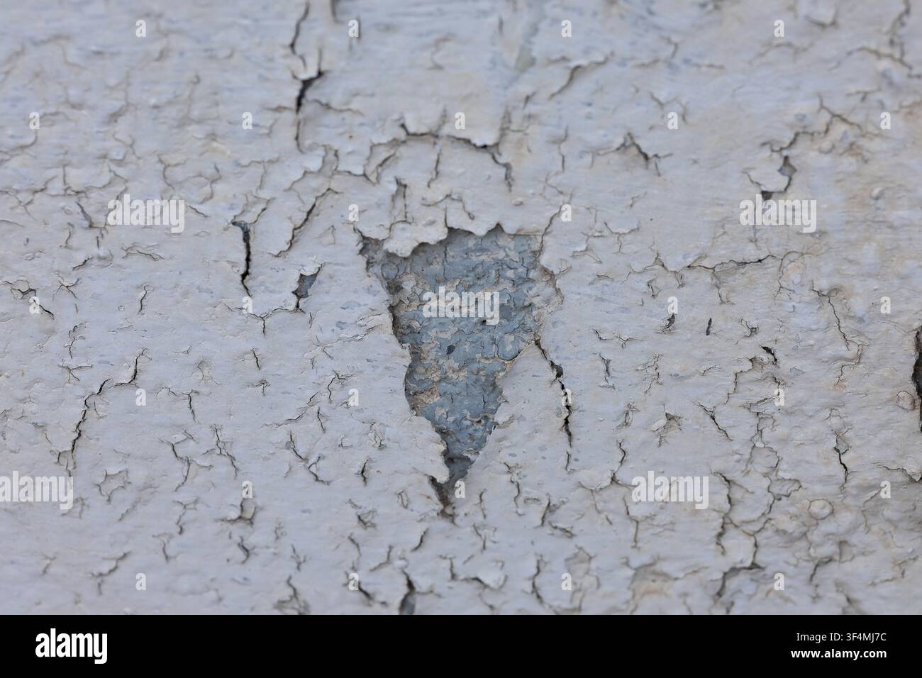 White paint peeling from an aged wall creating a distressed background texture Stock Photo