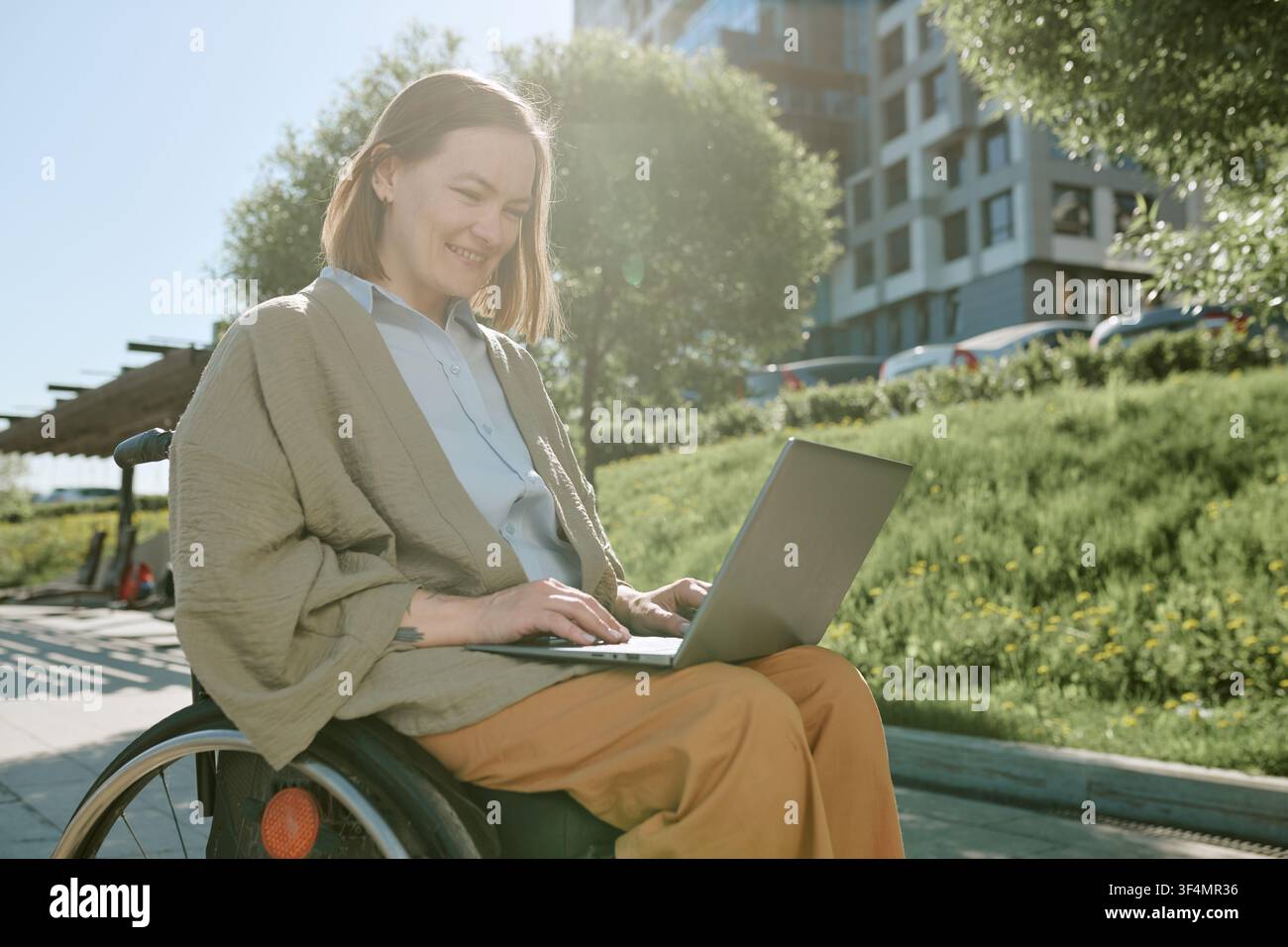 Woman with Disability Using Laptop Outdoors for Remote Work Stock Photo