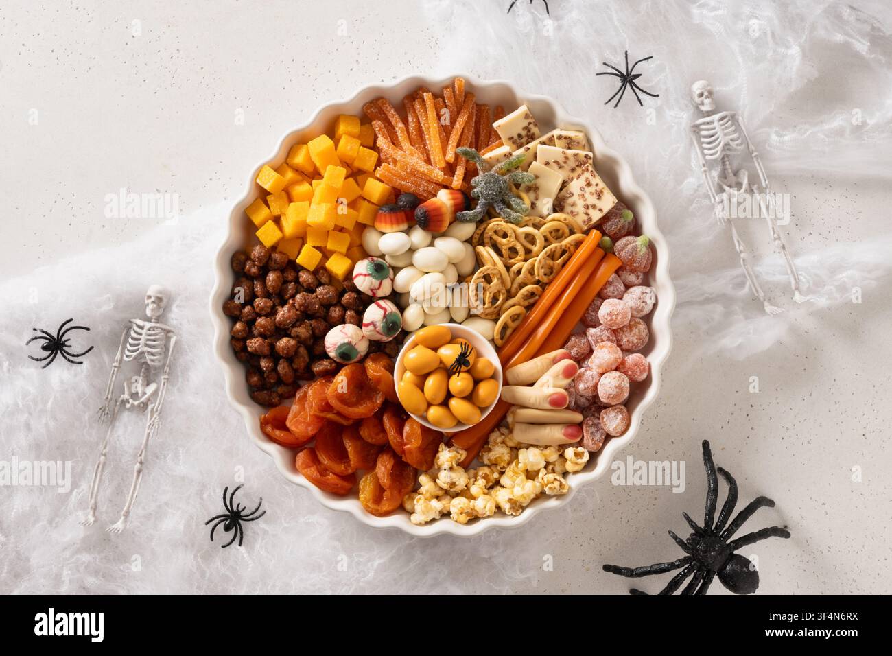 Halloween sweet charcuterie board with pumpkins sweet chocolate candy, spider, crackers on white background. View from above. Stock Photo