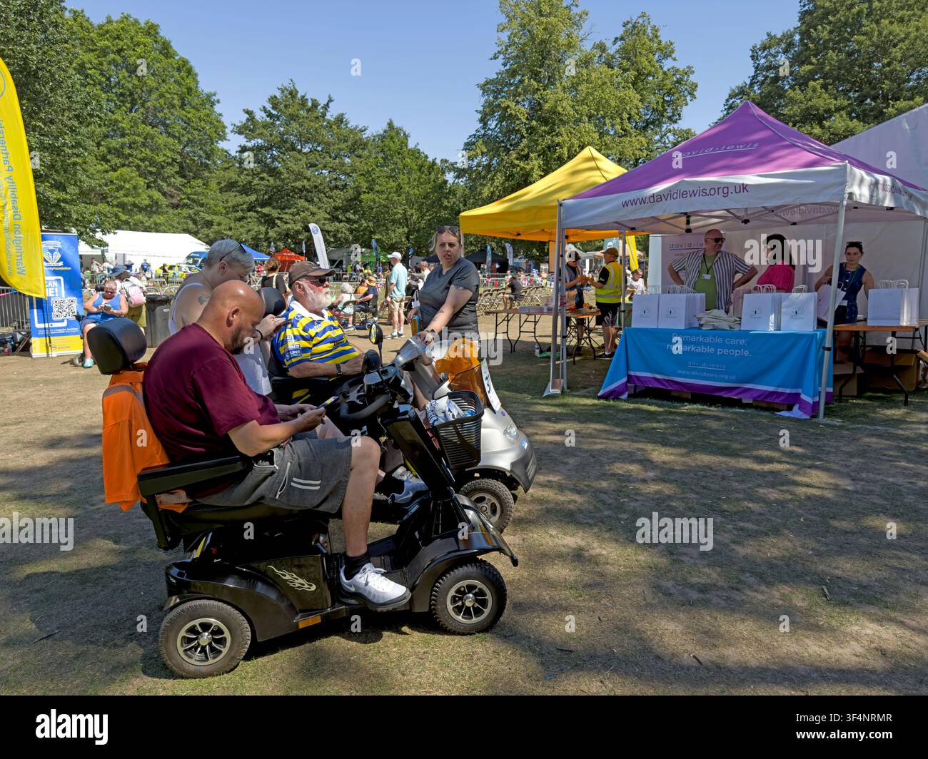 Visitors using mobility scooters at Disability Awareness Day 2026 in Walton Gardens, Warrington, Cheshire, with charity and information stalls Stock Photo