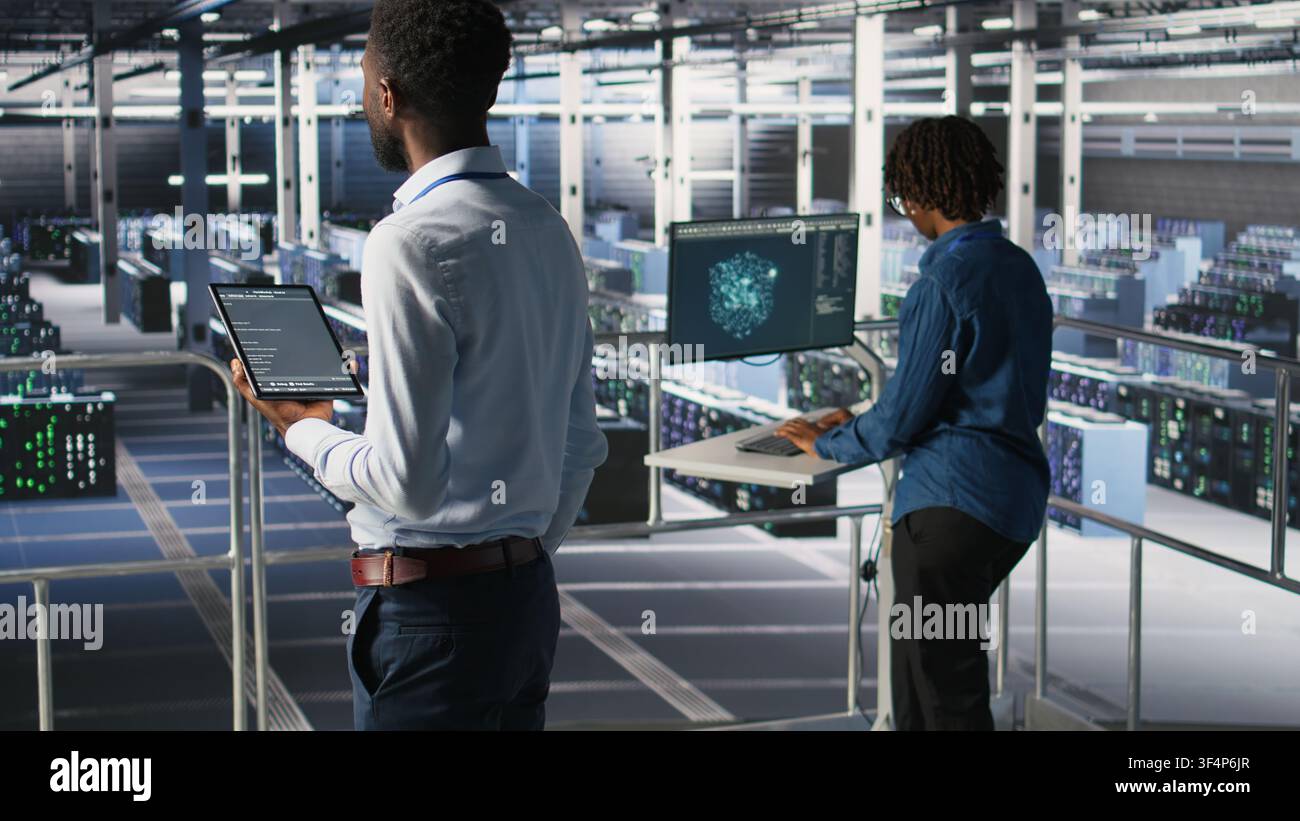 Data center programmer checking lines of code and colleague reviewing AI LLM visualizations. IT experts analyze neural networks outputs to ensure stable infrastructure operations, using tablet Stock Photo