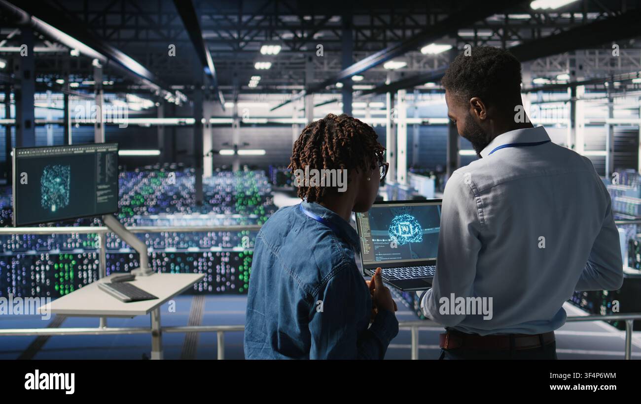 Data center engineering team doing maintenance on rigs handling AI processing tasks. Server hub teamworking colleagues managing storage arrays supporting deep learning training workflows, Stock Photo