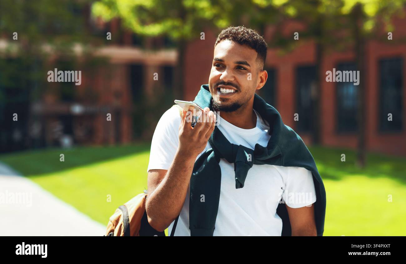 Smiling African American Man Talking On Smartphone With Hands Free Device Outdoors Stock Photo