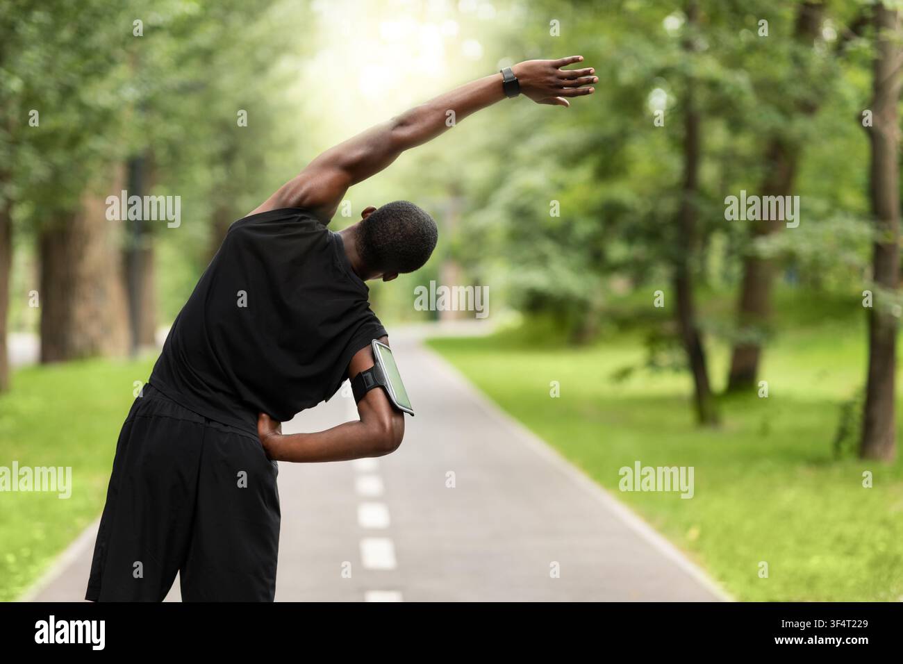 Black sportsman exercising before jogging, back view Stock Photo