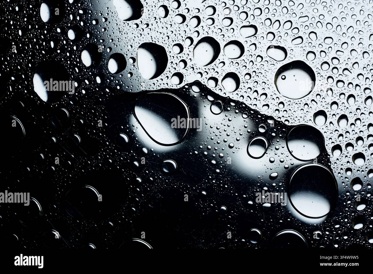 Water droplets forming an abstract pattern on a reflective surface Stock Photo