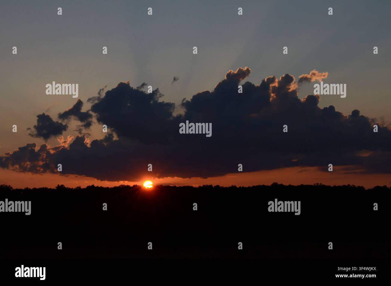 Sunset through Cumulus Clouds Stock Photo