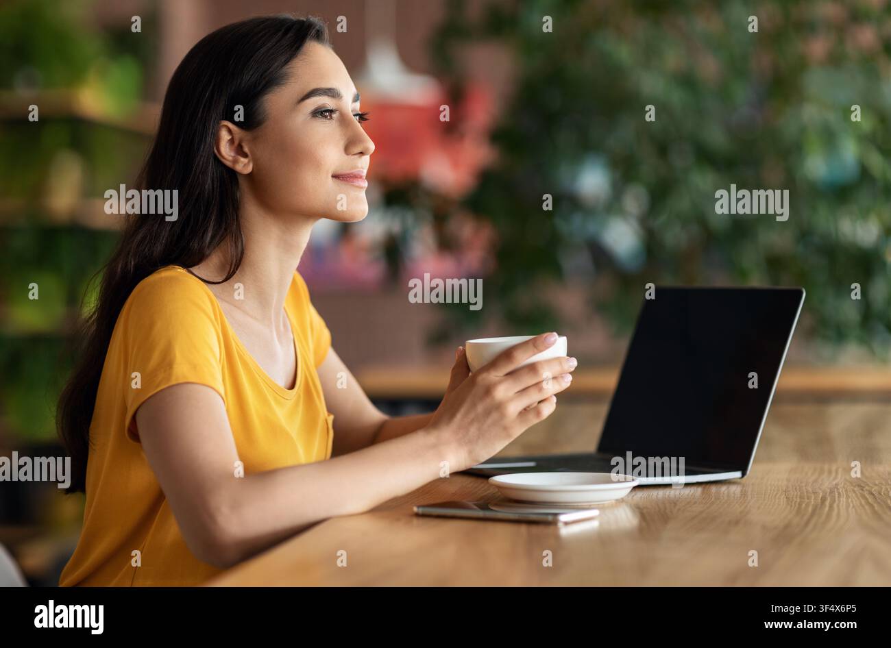 Happy young lady using laptop at cafe Stock Photo