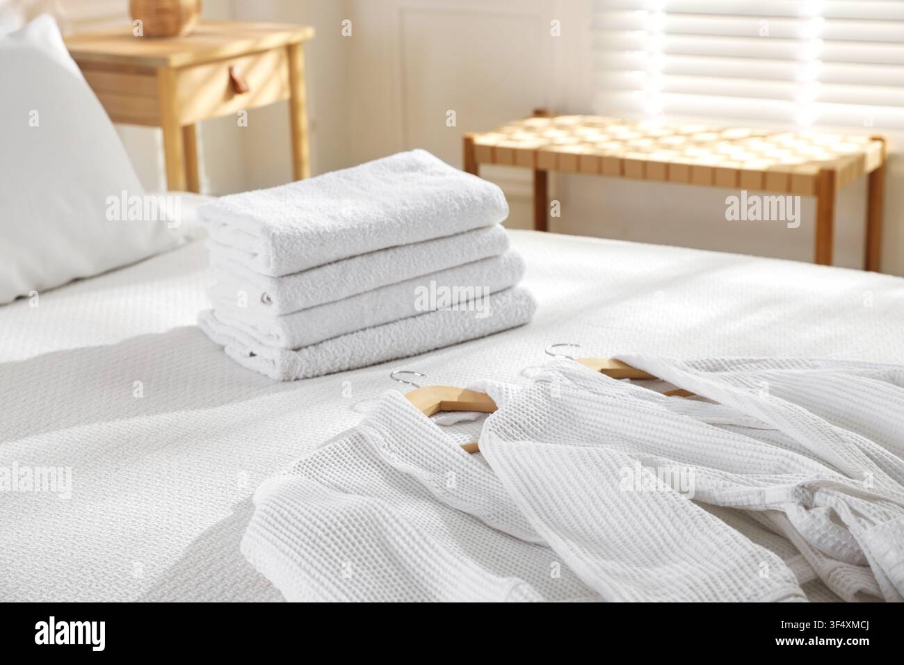 Clean bathrobes and towels on bed indoors Stock Photo