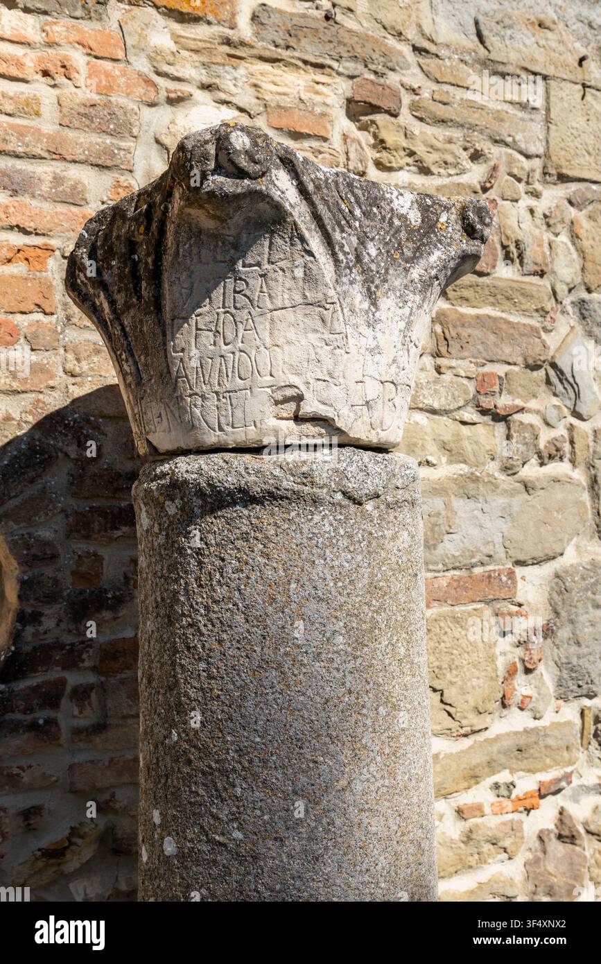 Weathered stone column capital featuring old inscriptions against a rustic wall Stock Photo