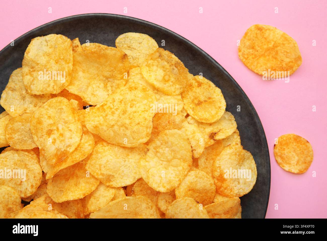Potato chips on plate on pink background. Top view Stock Photo