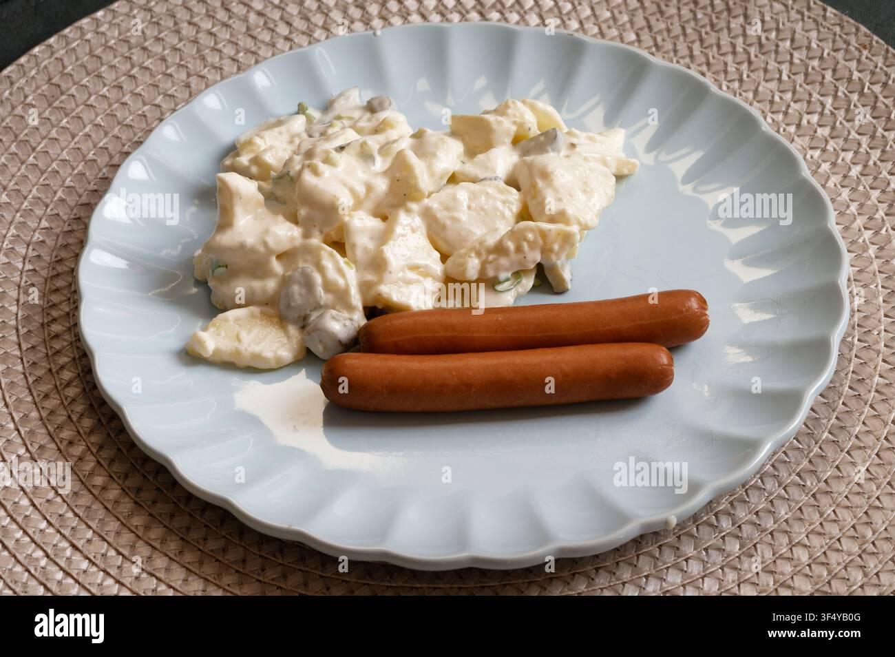 Creamy potato salad with mayo and spring onions served with two hot dogs on a plate. Traditional simple meal. Stock Photo