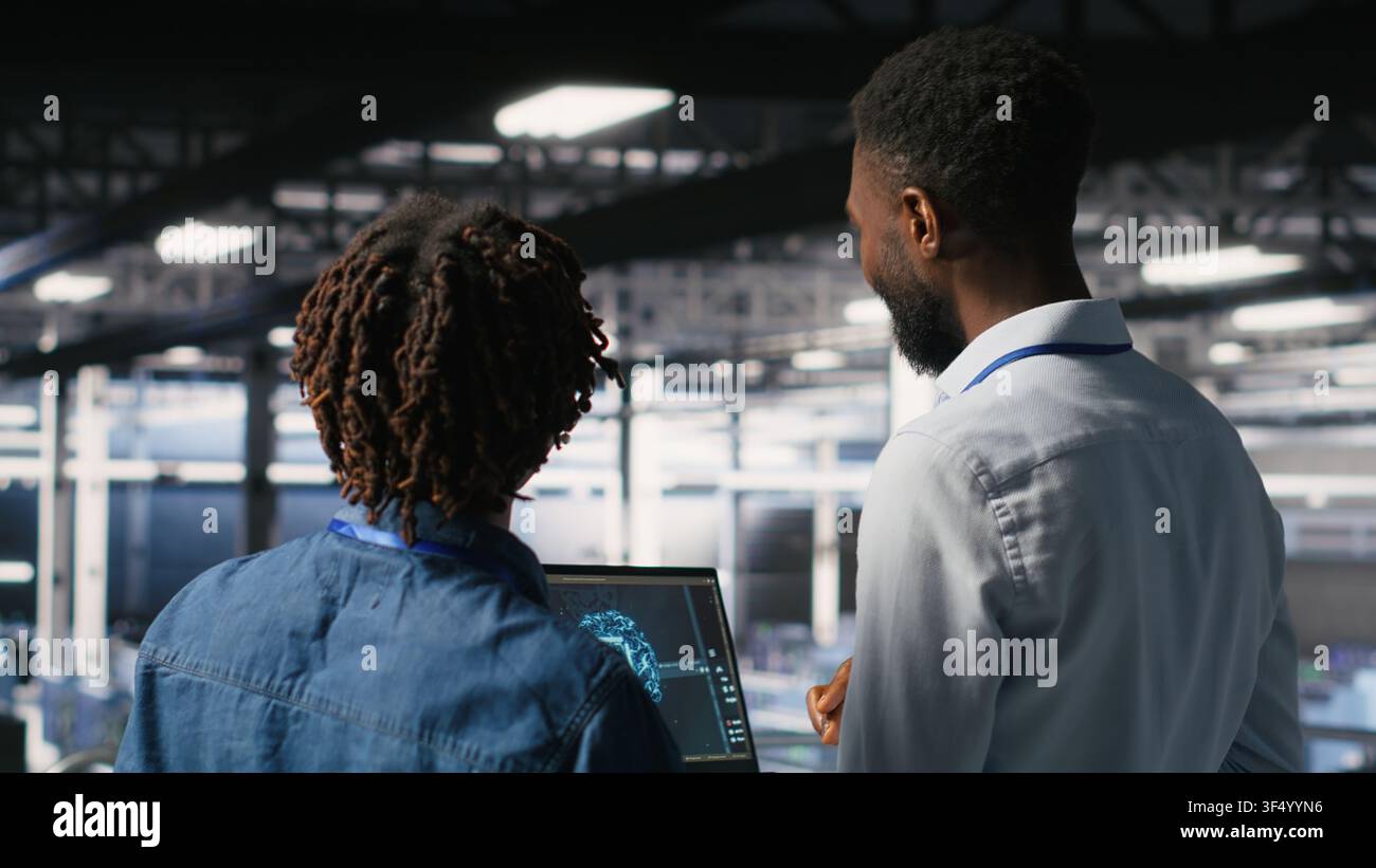 Data center engineering team doing maintenance on rigs handling AI processing tasks. Server hub teamworking colleagues managing storage arrays supporting deep learning training workflows Stock Photo