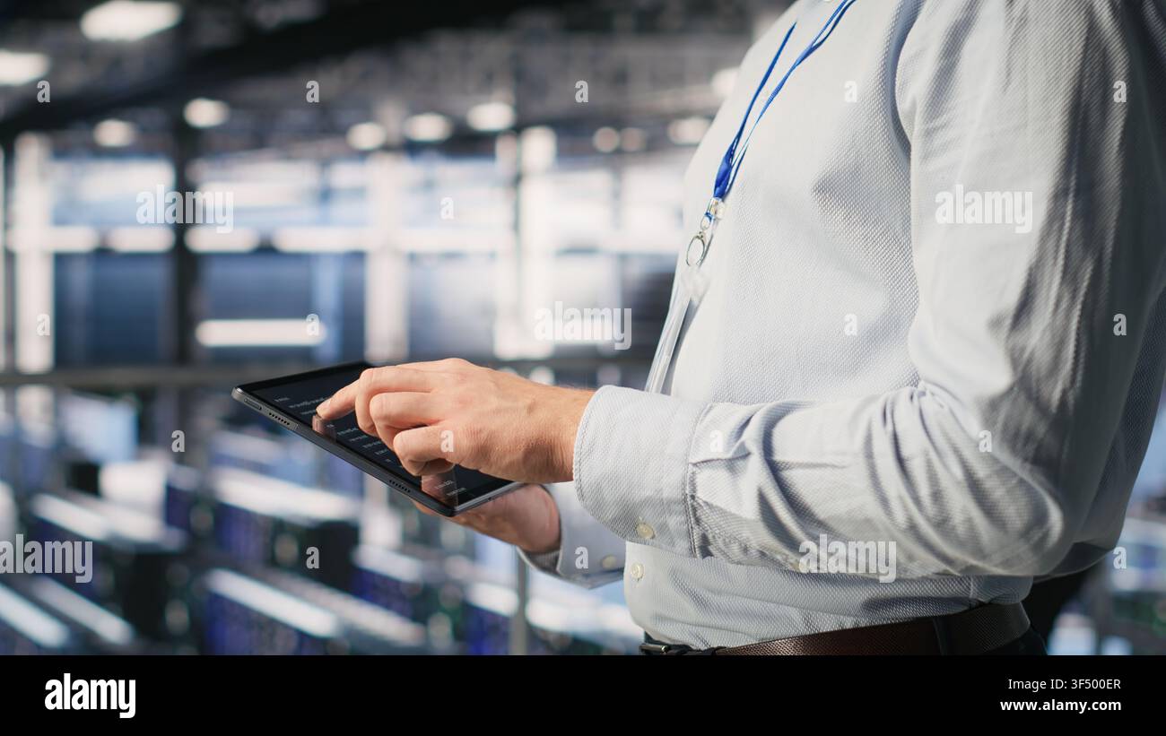 Programmers on data center industrial platform checking code on tablet, doing software updates. Server farm IT professionals cooperating, finetuning rackmounts configurations Stock Photo