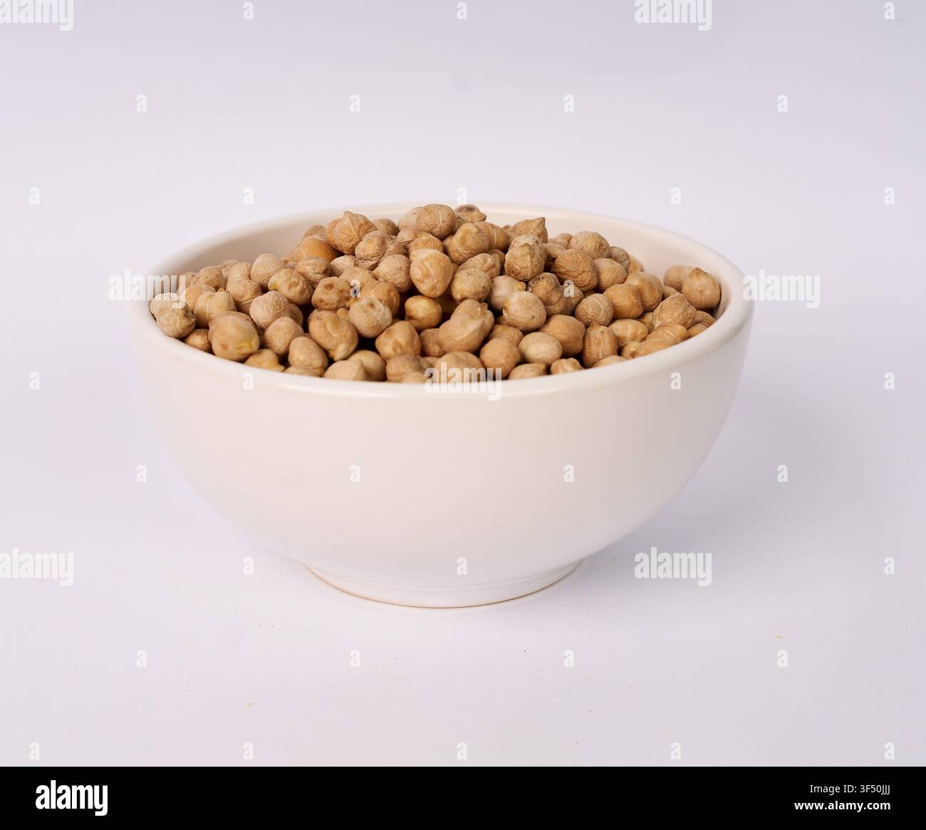 White ceramic bowl filled with dried chickpeas isolated on white background Stock Photo