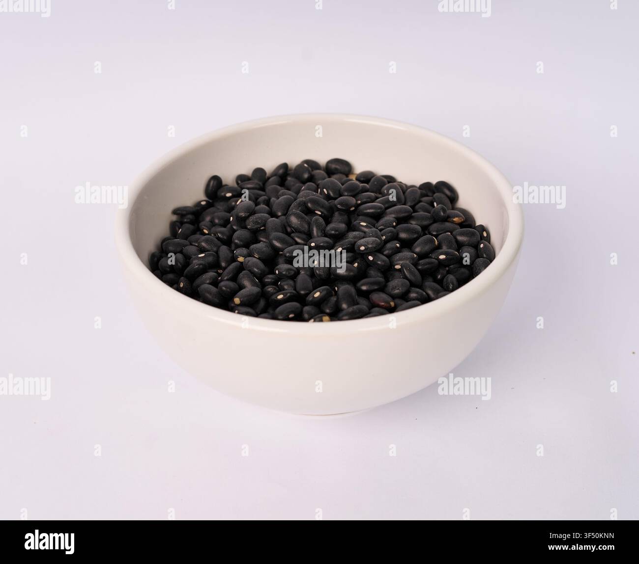 Ceramic bowl filled with dried black beans isolated on white background Stock Photo