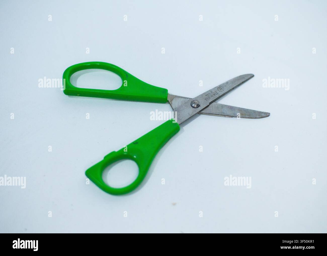Hand Holding Green Plastic Handled Scissors Isolated on White Background Stock Photo