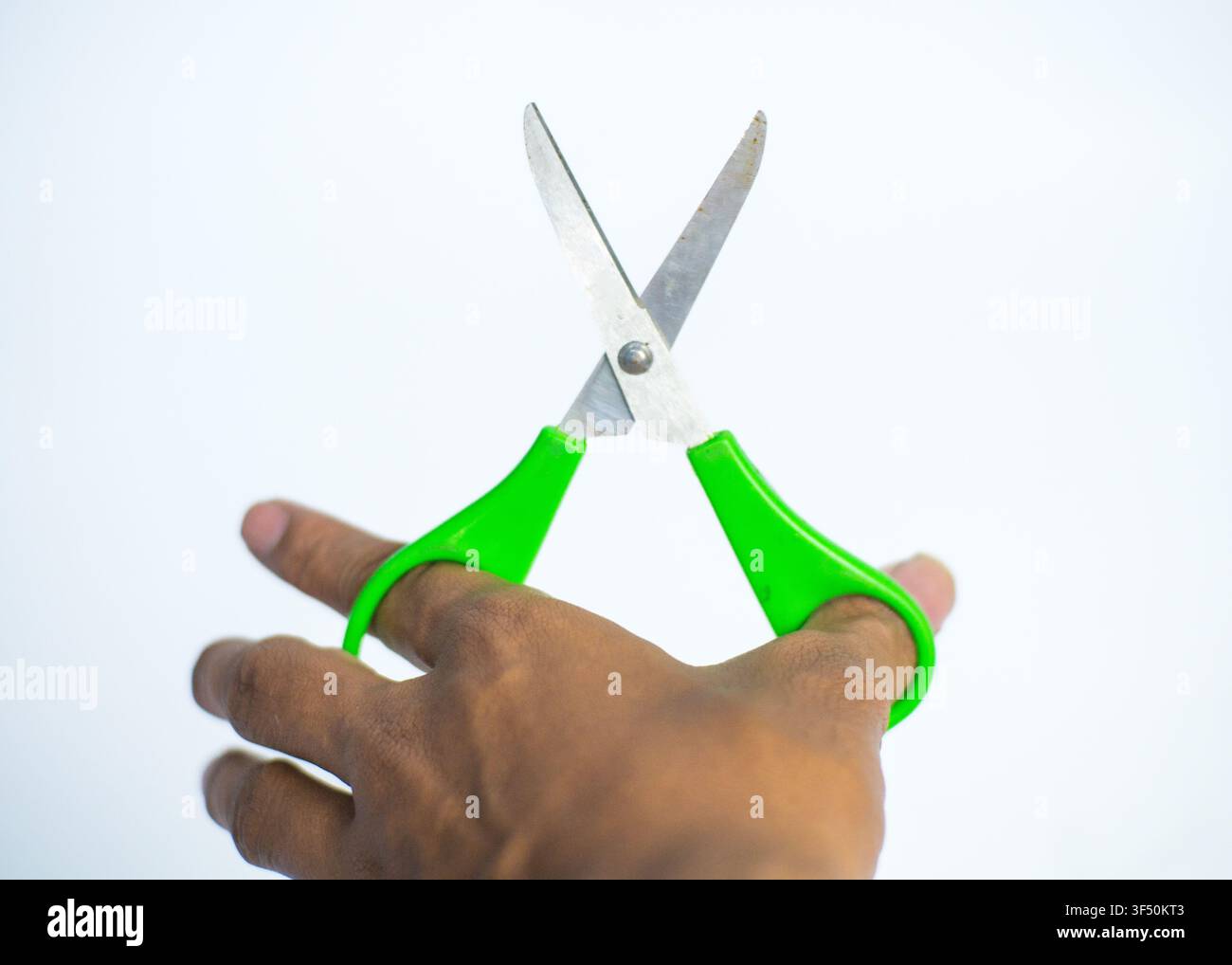 Hand Holding Green Plastic Handled Scissors Isolated on White Background Stock Photo