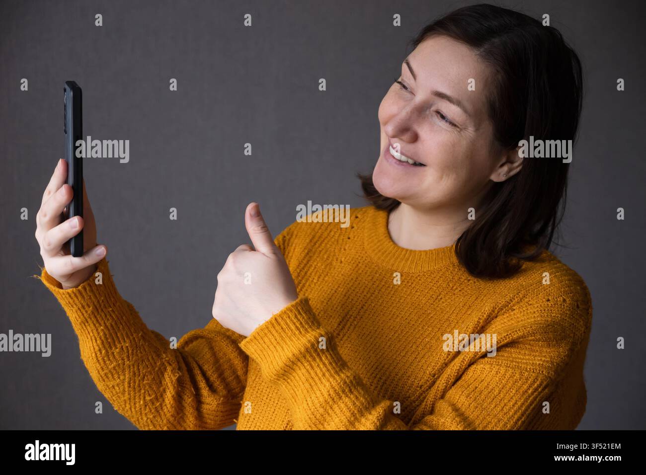 Pregnant woman smiling while taking a selfie with a smartphone Stock Photo