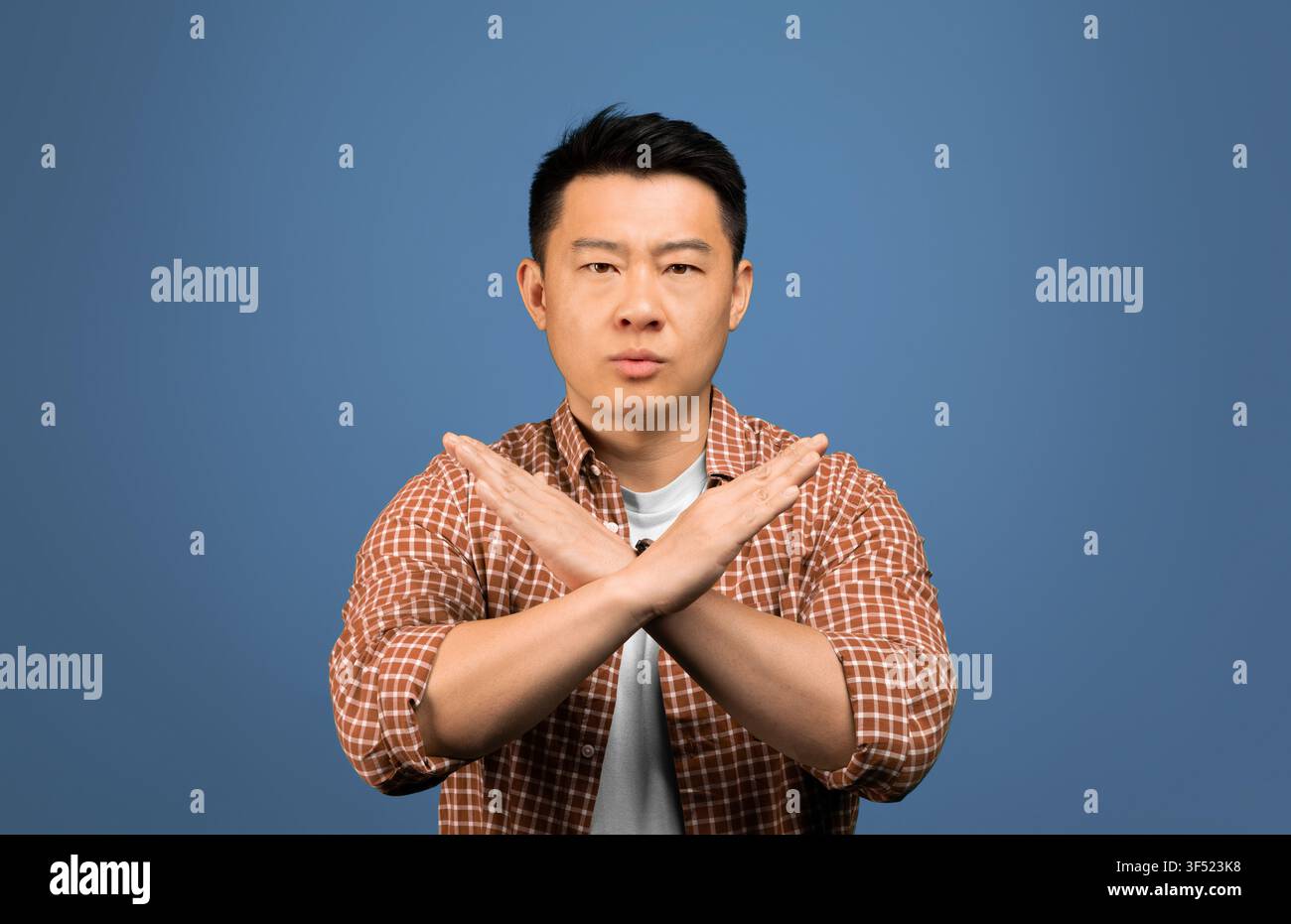 Man Standing With Arms Crossed, Serious Expression, Studio Background, Business Concept Stock Photo