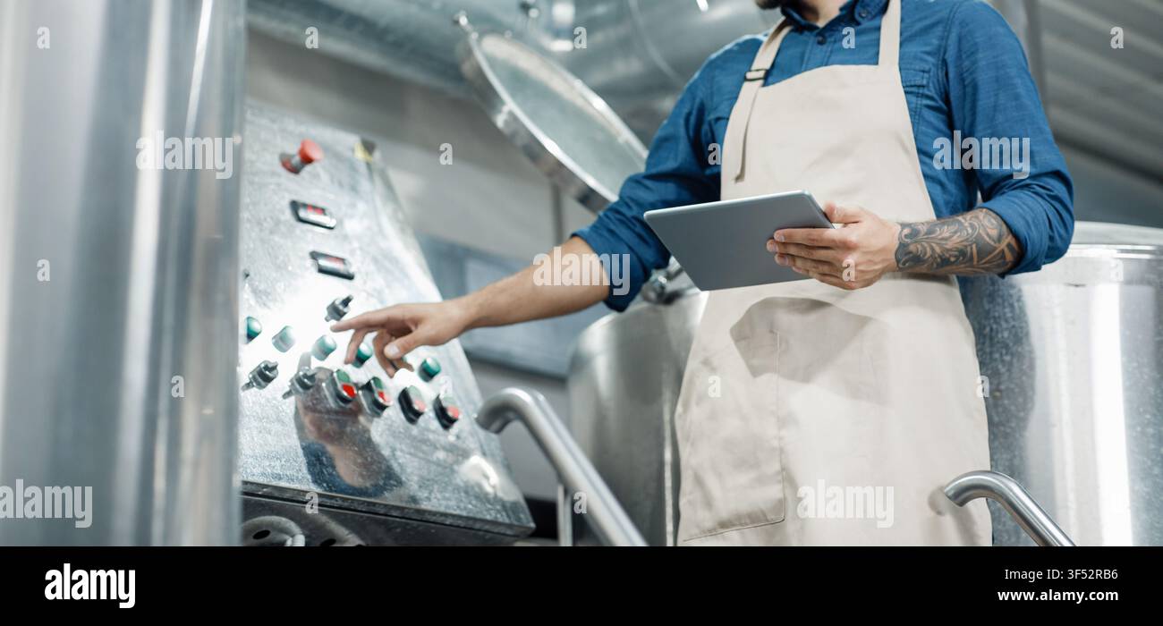 Man With Tattoo Operating Control Panel In Industrial Setting, Focused On Work Process Stock Photo