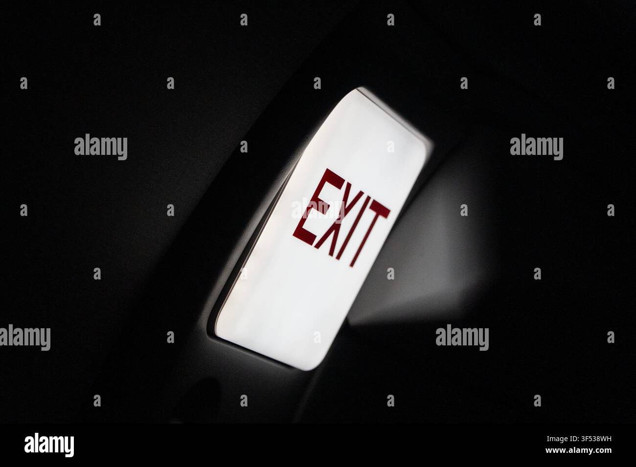 A bright EXIT sign illuminates a dark space. Stock Photo