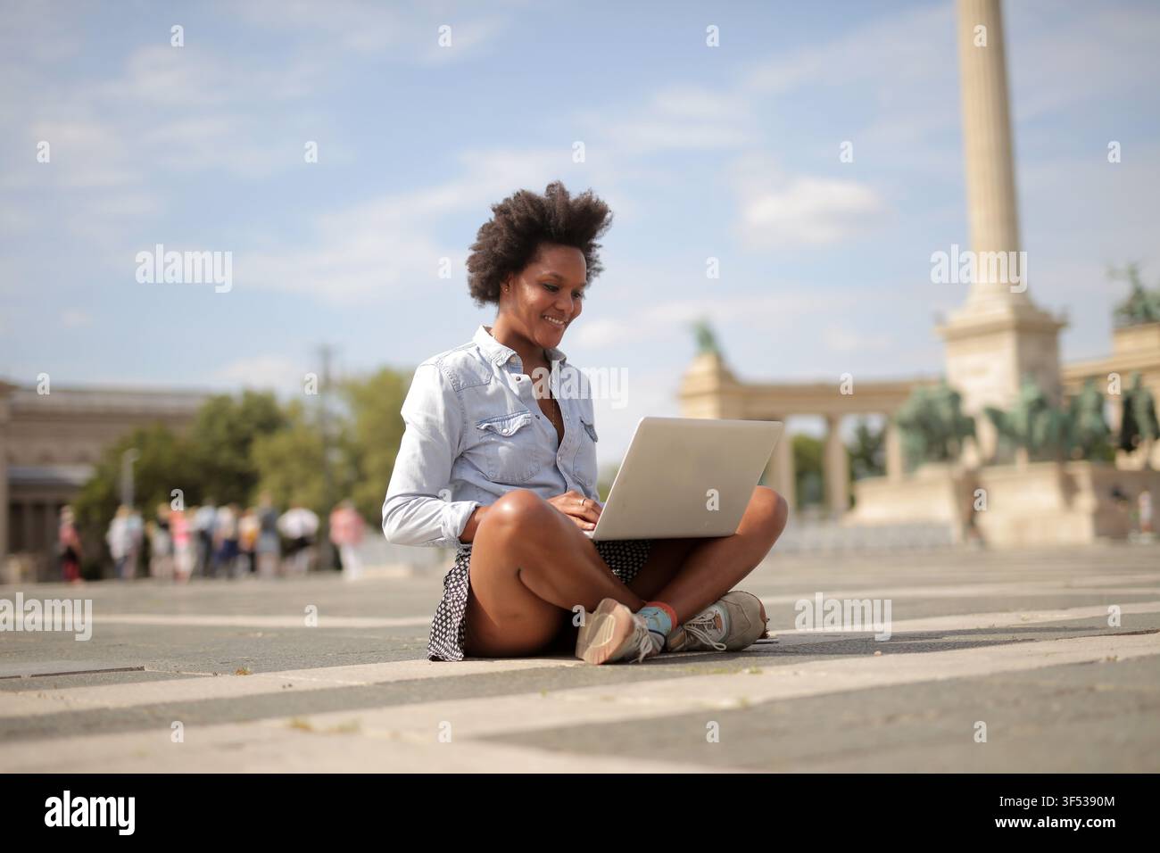 Happy young woman working on laptop in Budapest Stock Photo