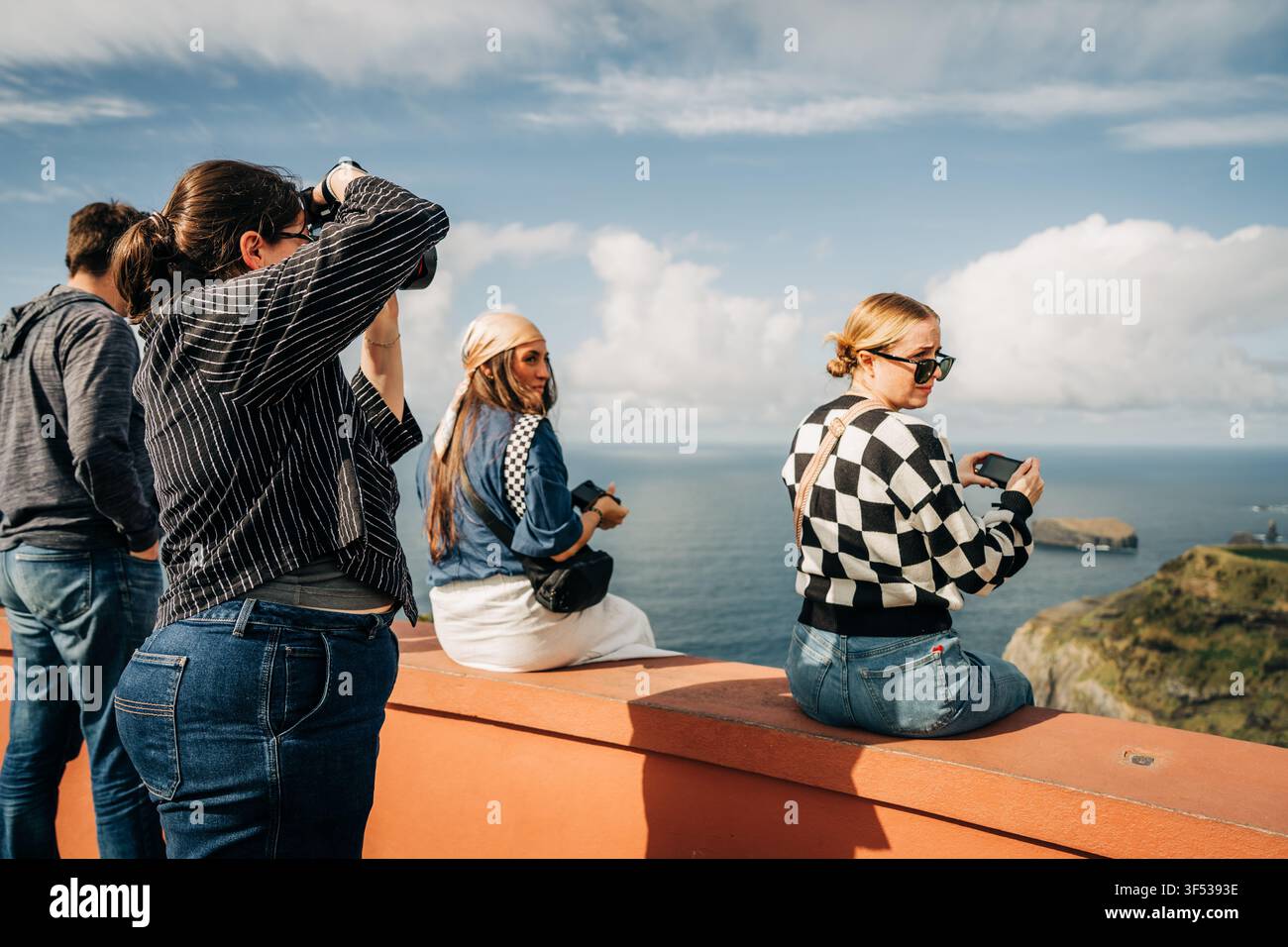 Friends take photos at scenic ocean viewpoint Stock Photo