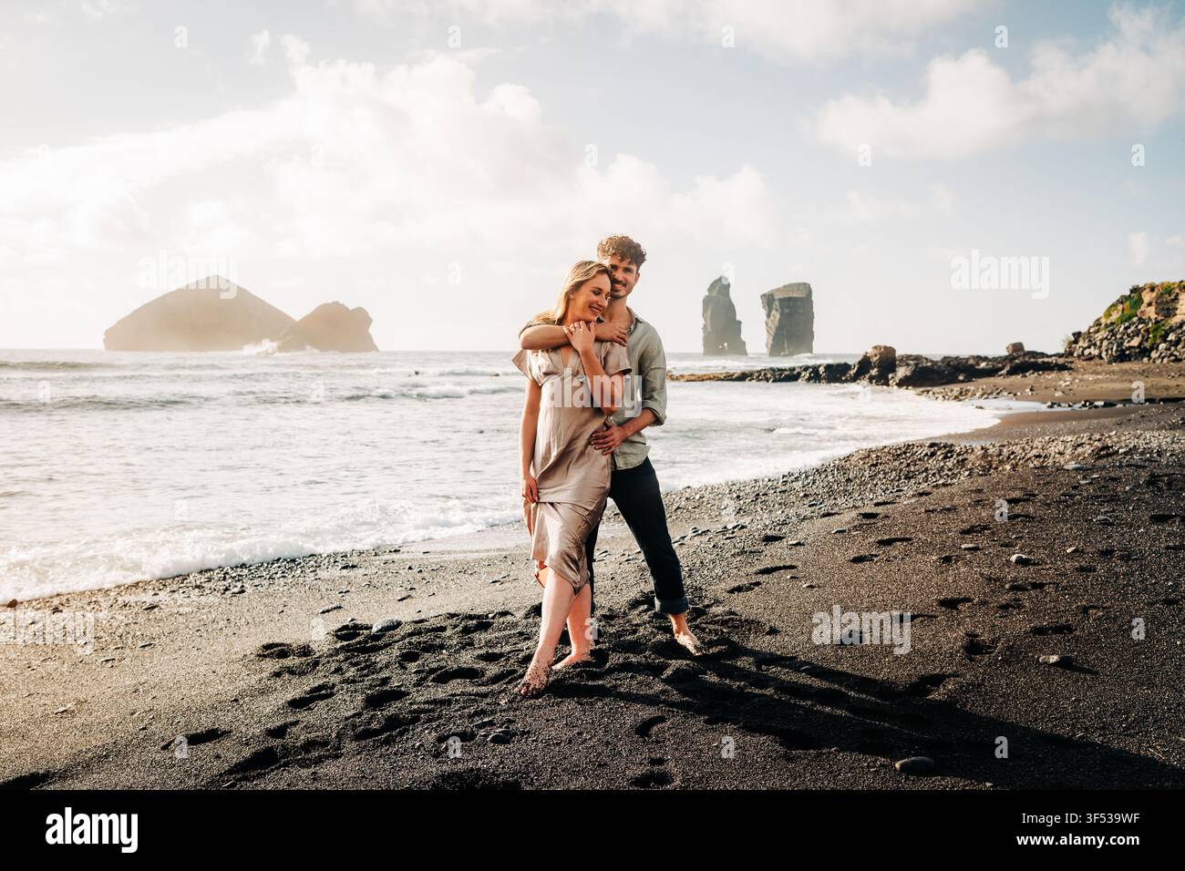 Happy young couple embracing on a black sand beach Stock Photo