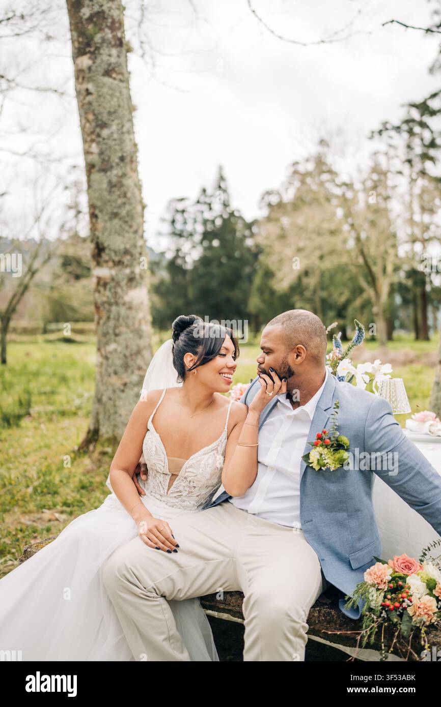 Bride affectionately touches groom's face outside Stock Photo