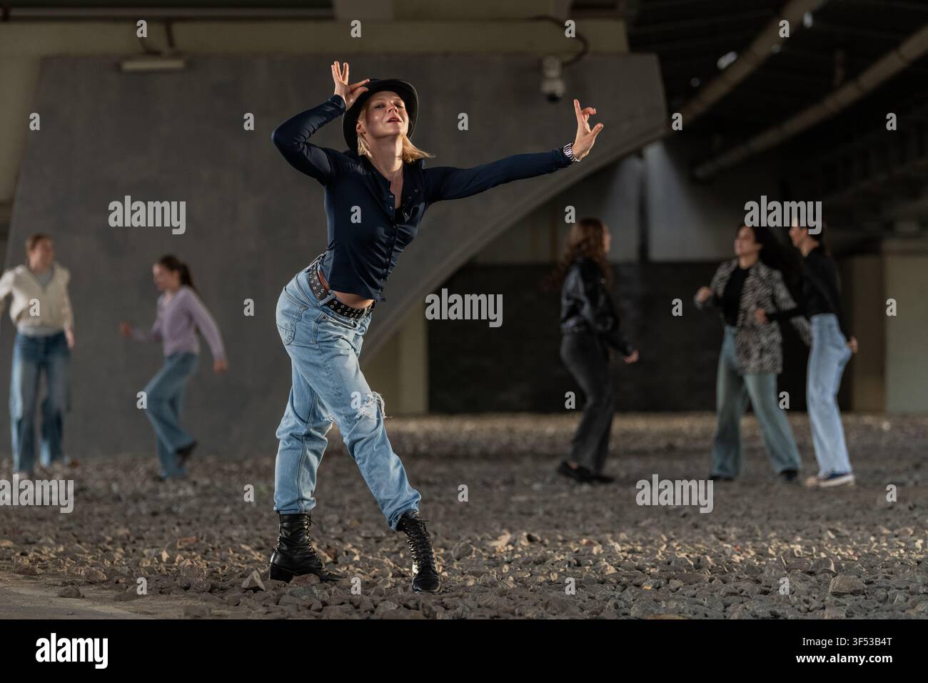 Expressive female dancer striking a pose under a bridge Stock Photo
